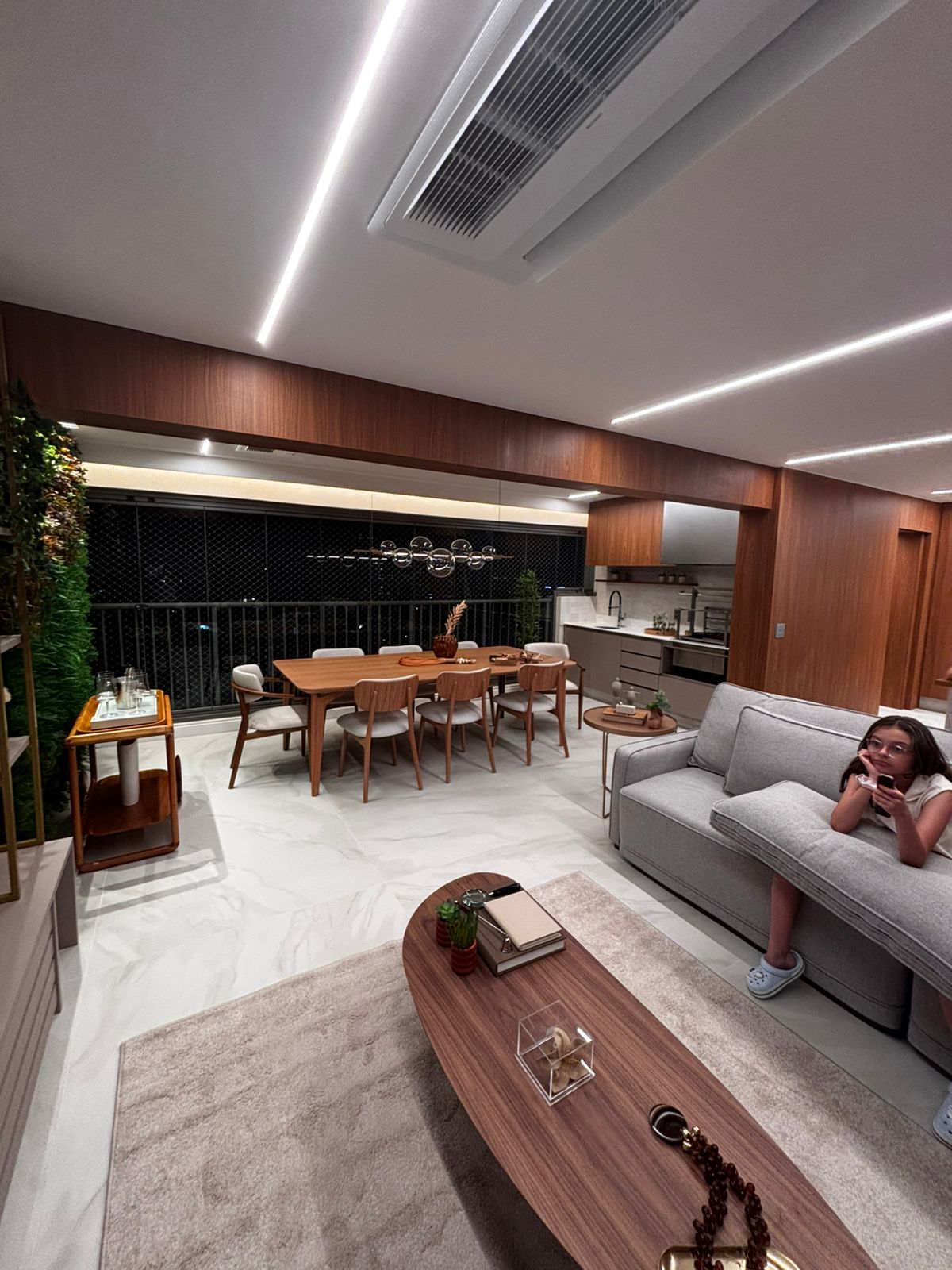 Bar ou cantinho do café planejado em nicho de madeira, com balcão cinza escuro e armário aéreo com porta de vidro.