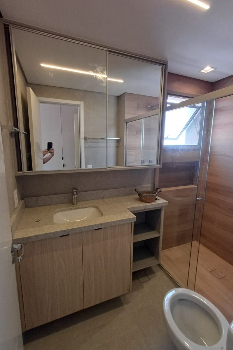 Vista lateral de banheiro sob medida, mostrando a integração harmônica entre a marcenaria e o revestimento amadeirado do box.