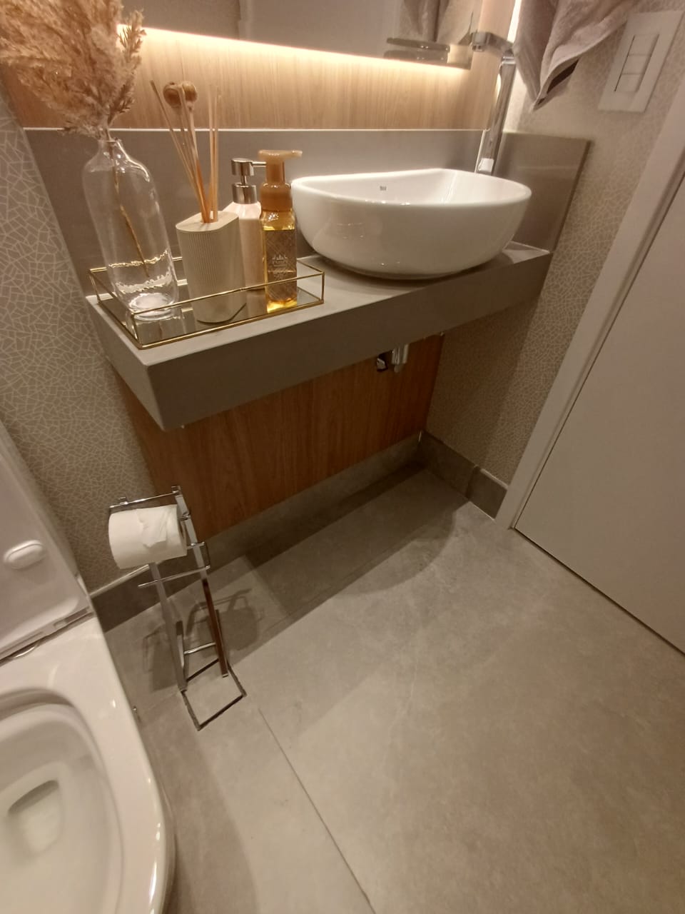 Gabinete de banheiro simples sob medida em tom amadeirado mogno, com tampo de granito e cuba de embutir oval.