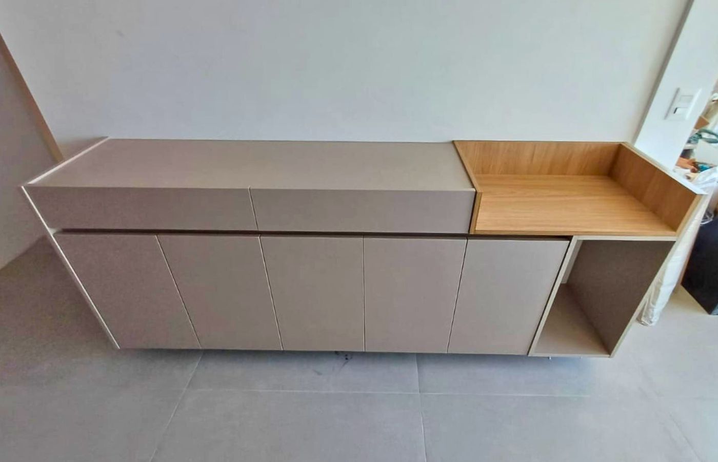 Buffet ou balcão planejado baixo com tampo amadeirado e portas em tom nude, versátil para sala de jantar.