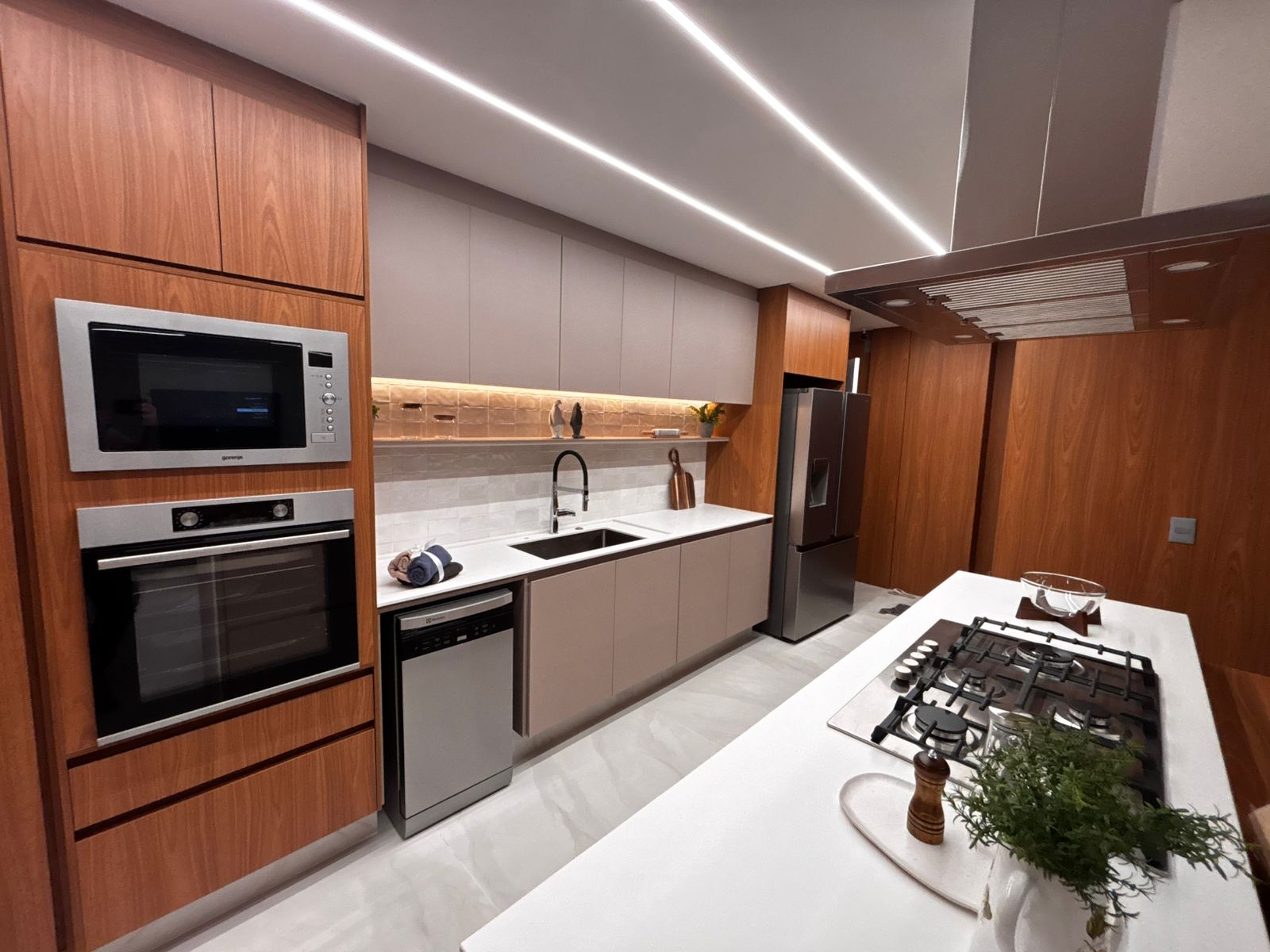 Cozinha gourmet planejada de alto padrão com ilha central, armários brancos e estrutura metálica suspensa (estilo industrial).