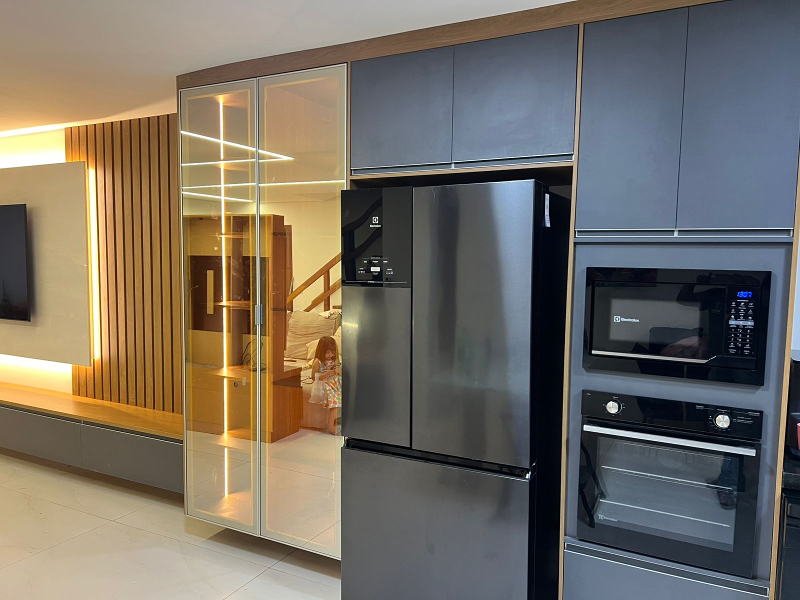 Cozinha gourmet planejada de alto padrão com ilha central, armários brancos e estrutura metálica suspensa (estilo industrial).