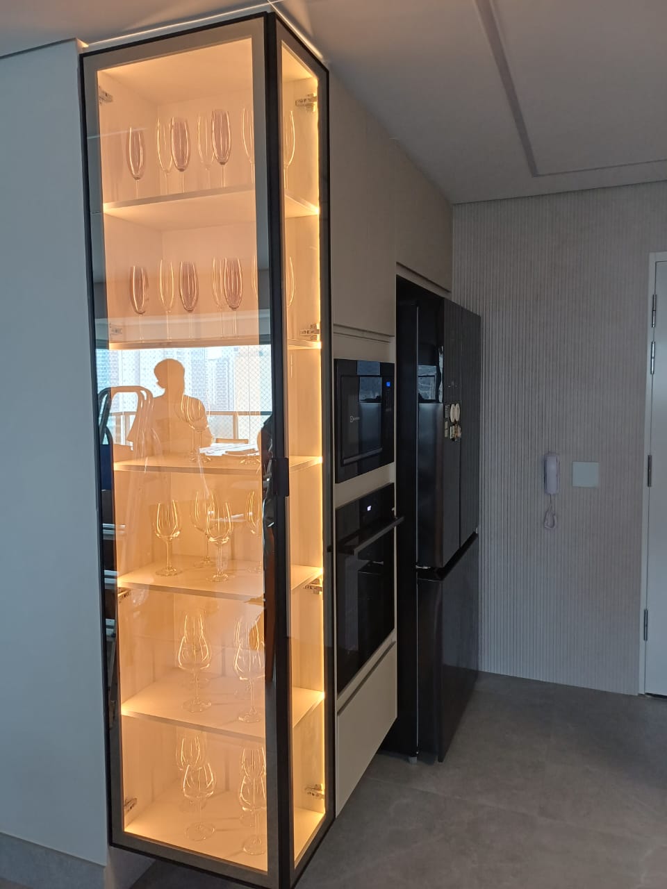 Cozinha gourmet planejada de alto padrão com ilha central, armários brancos e estrutura metálica suspensa (estilo industrial).