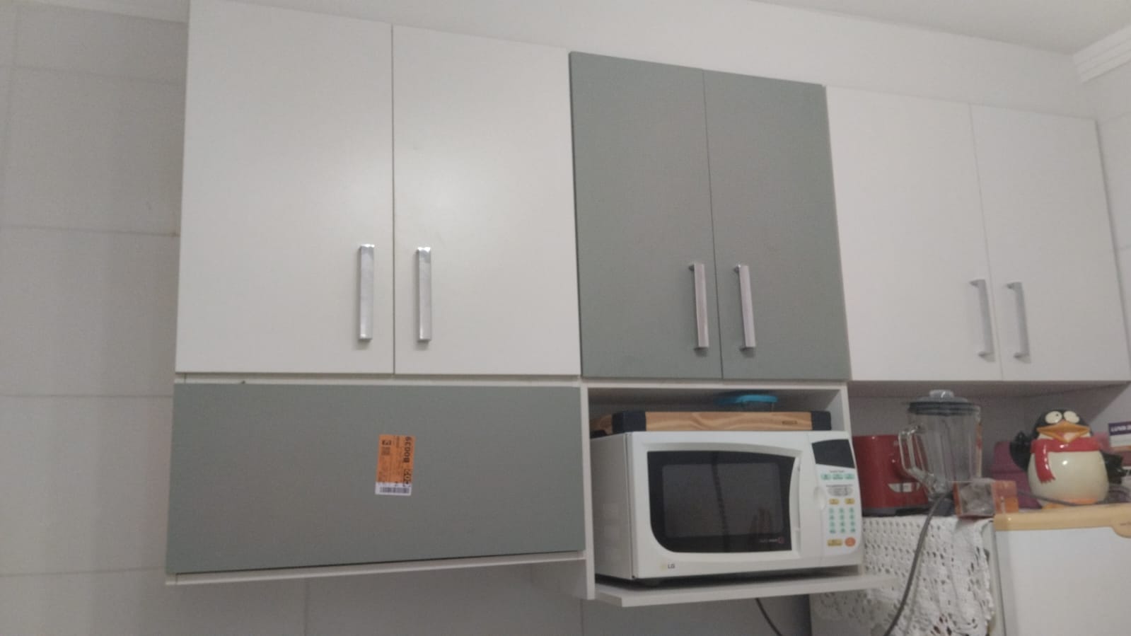 Cozinha gourmet planejada de alto padrão com ilha central, armários brancos e estrutura metálica suspensa (estilo industrial).