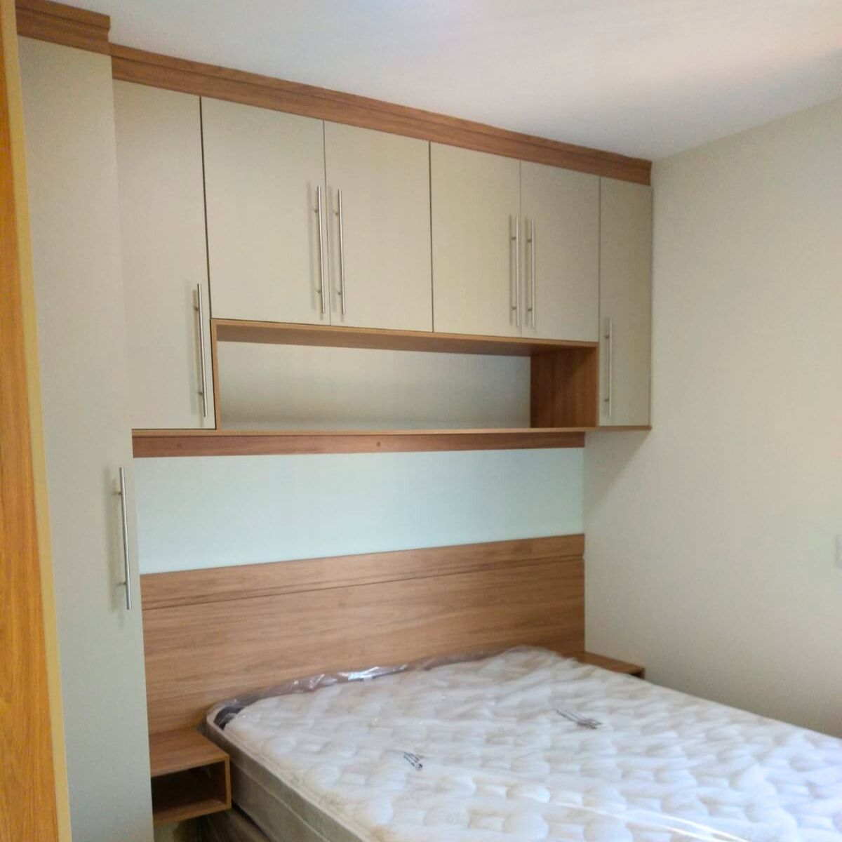 Detalhe de armários aéreos planejados sobre a cama, otimizando o espaço vertical em quartos pequenos.