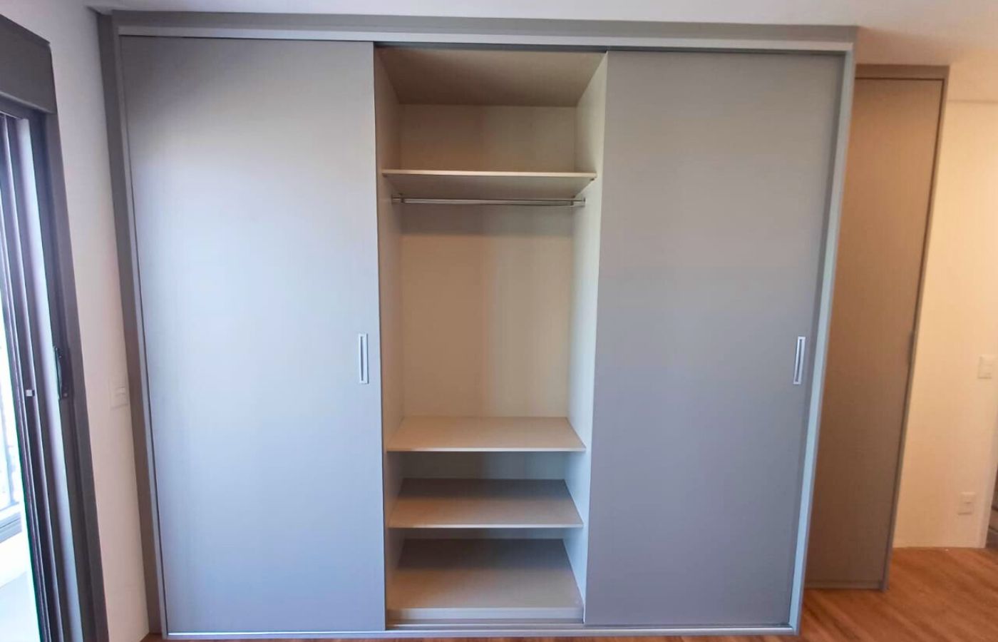 Guarda-roupa sob medida com portas de correr em tom neutro e nichos internos bem distribuídos para roupas e acessórios.