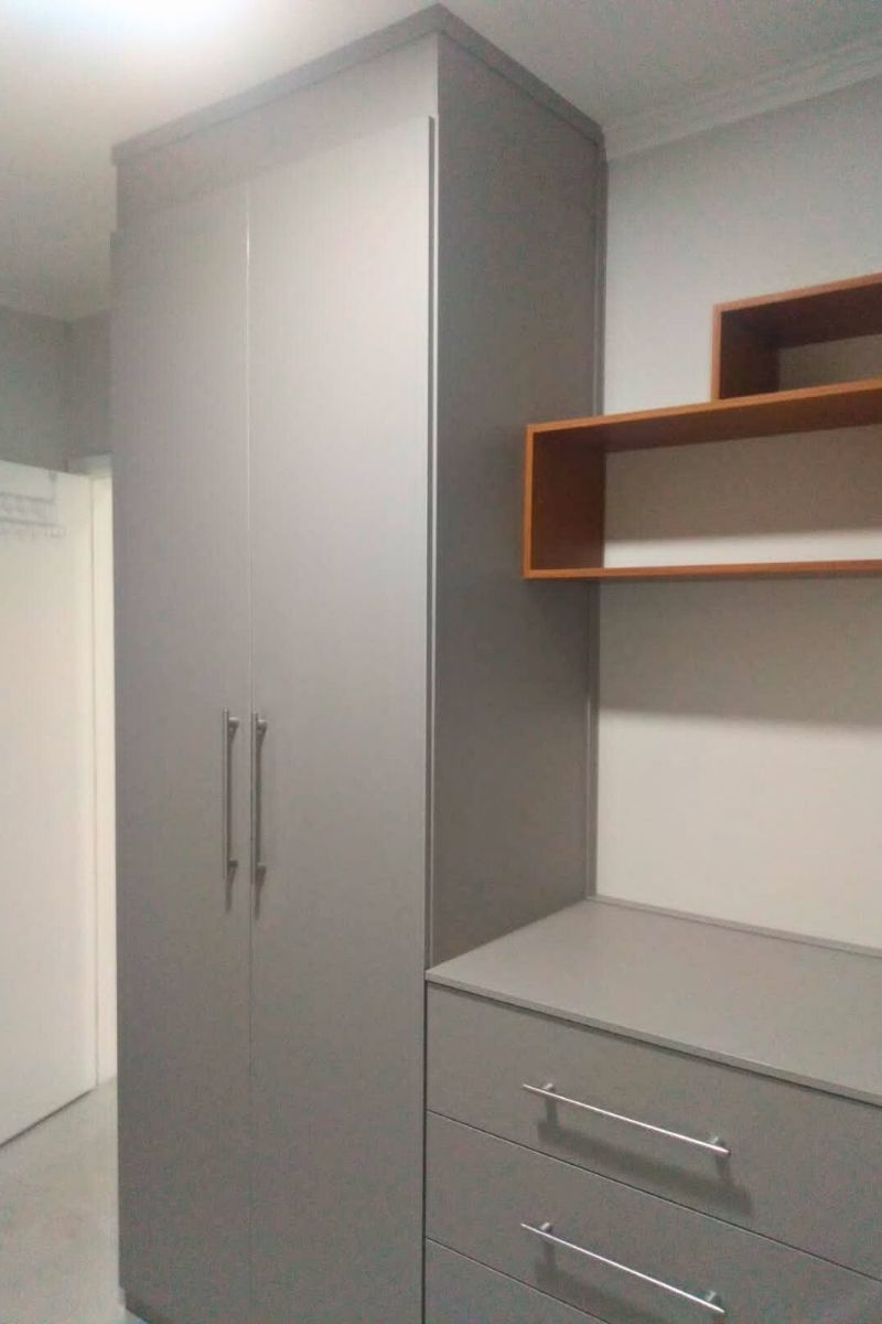 Detalhe de acabamento de armário planejado em tom cinza e madeira, mostrando o aproveitamento de espaço superior.