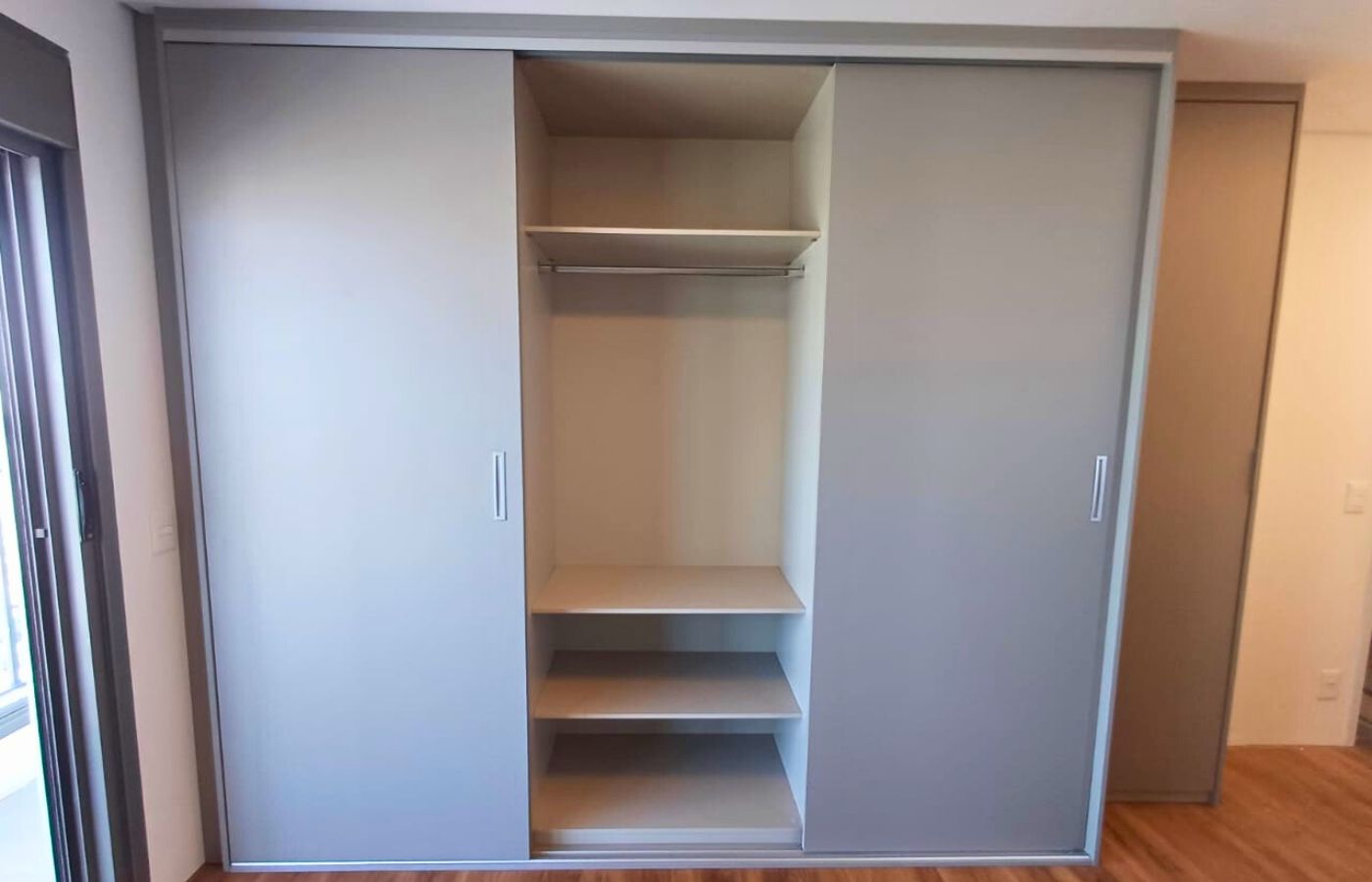 Vista interna de guarda-roupa planejado aberto, exibindo prateleiras e cabideiros para organização de roupas.