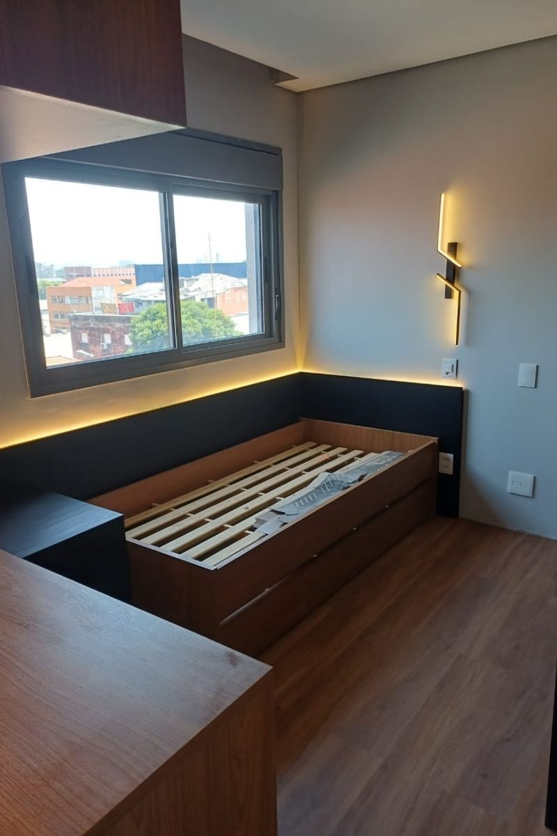 Estrutura de cama planejada (box) com estrado reforçado e cabeceira iluminada por fita de LED quente.