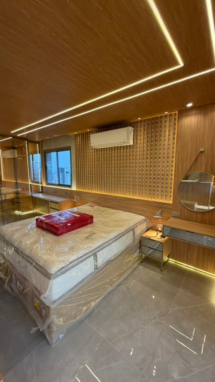 Penteadeira estilo camarim planejada, com espelho iluminado por lâmpadas e prateleiras em madeira, integrada ao quarto.