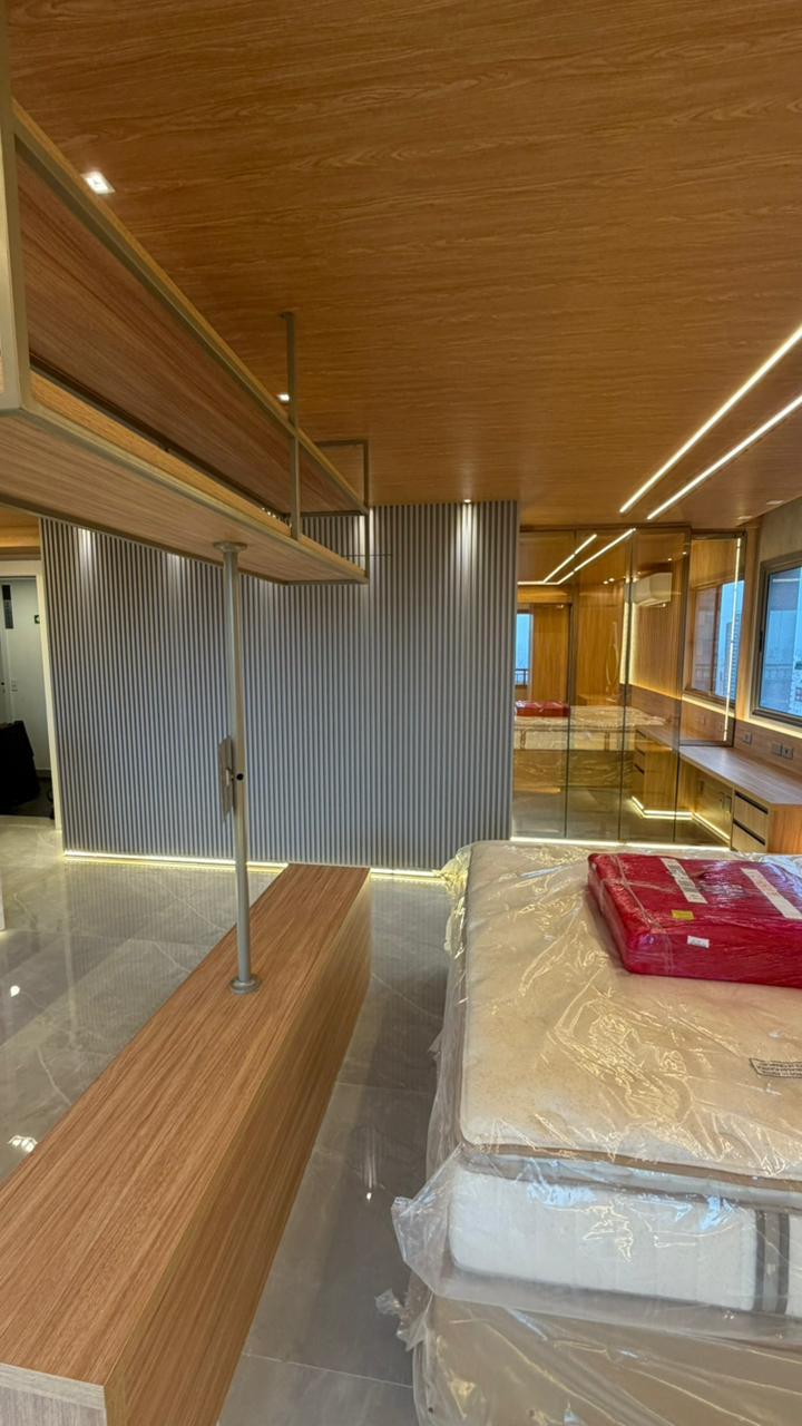 Detalhe de acabamento de armário planejado em tom cinza e madeira, mostrando o aproveitamento de espaço superior.