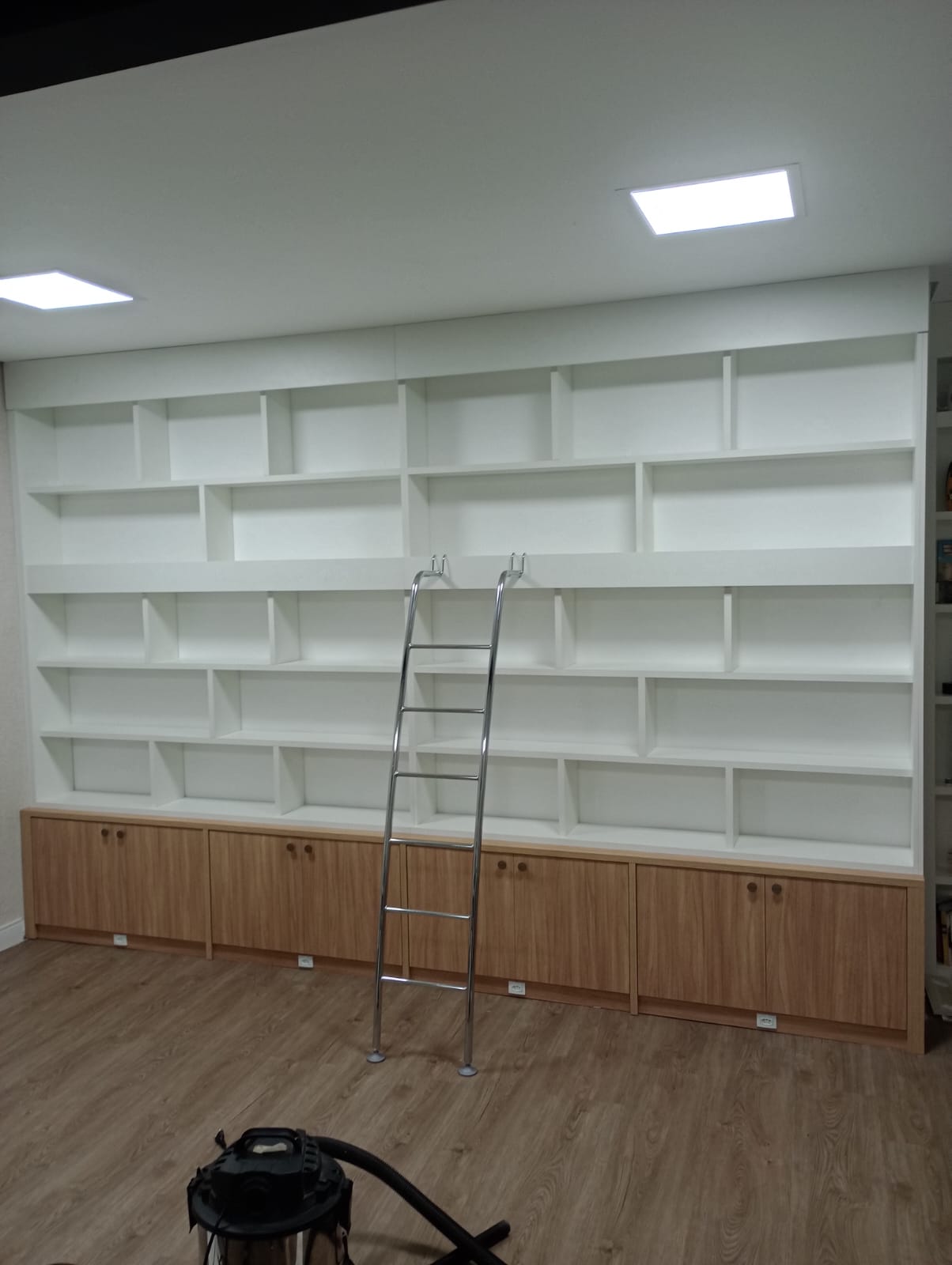 Quarto planejado de canto em tons claros (bege/branco), com armários em L otimizando o espaço do dormitório.