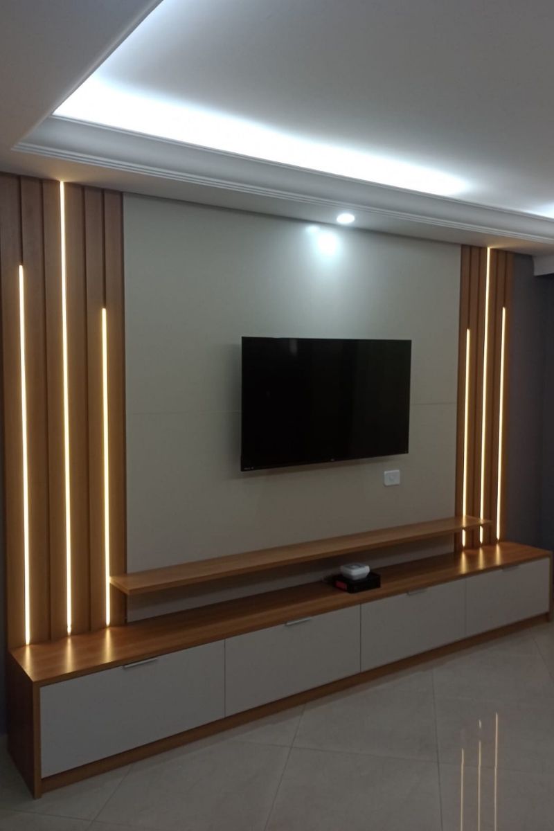 Painel de TV planejado moderno com detalhes em madeira ripada vertical e iluminação LED embutida nas laterais.