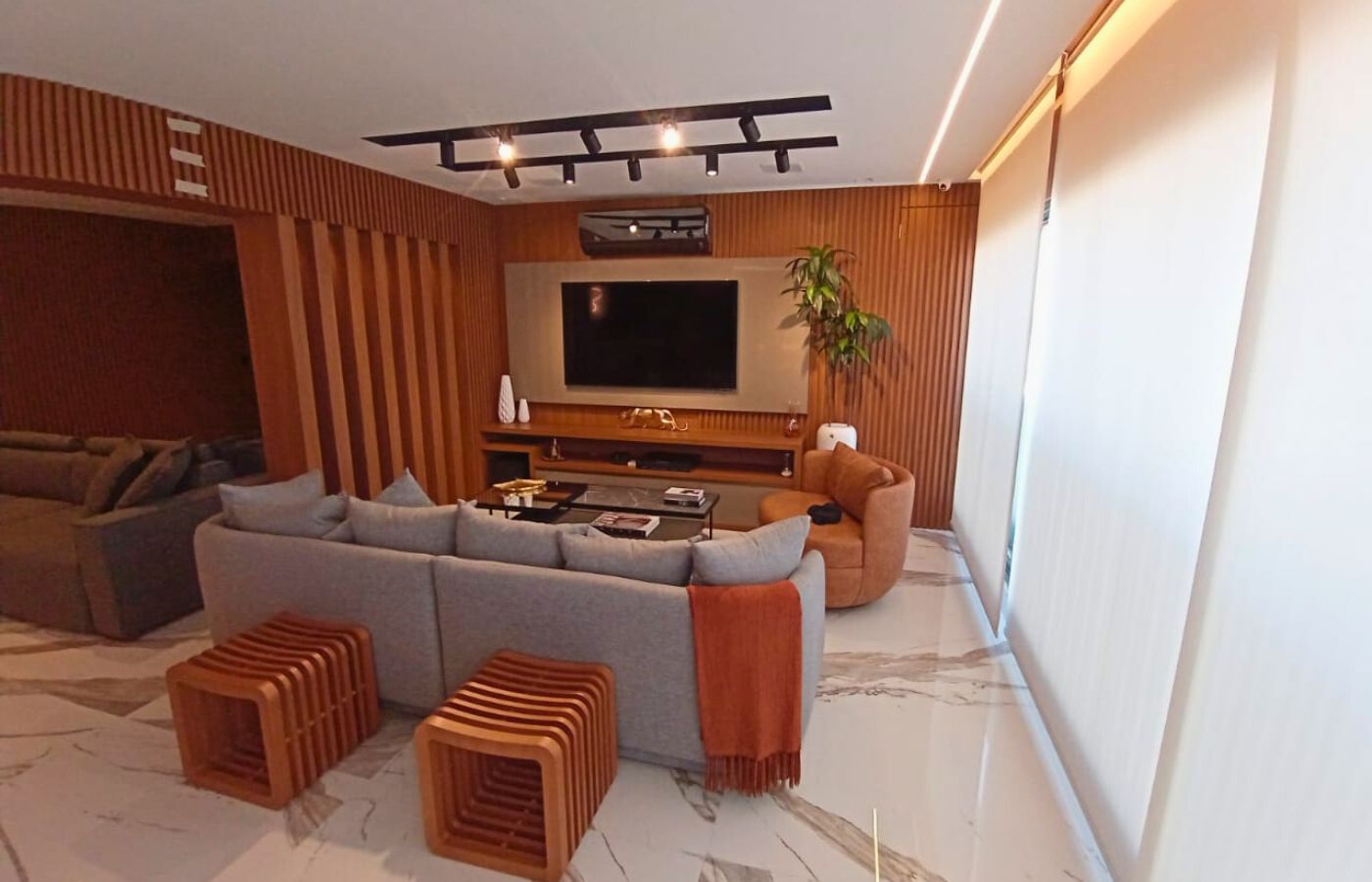 Painel de TV planejado moderno com detalhes em madeira ripada vertical e iluminação LED embutida nas laterais.