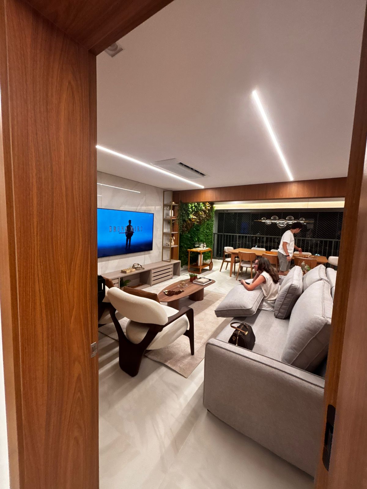 Painel de TV planejado moderno com detalhes em madeira ripada vertical e iluminação LED embutida nas laterais.