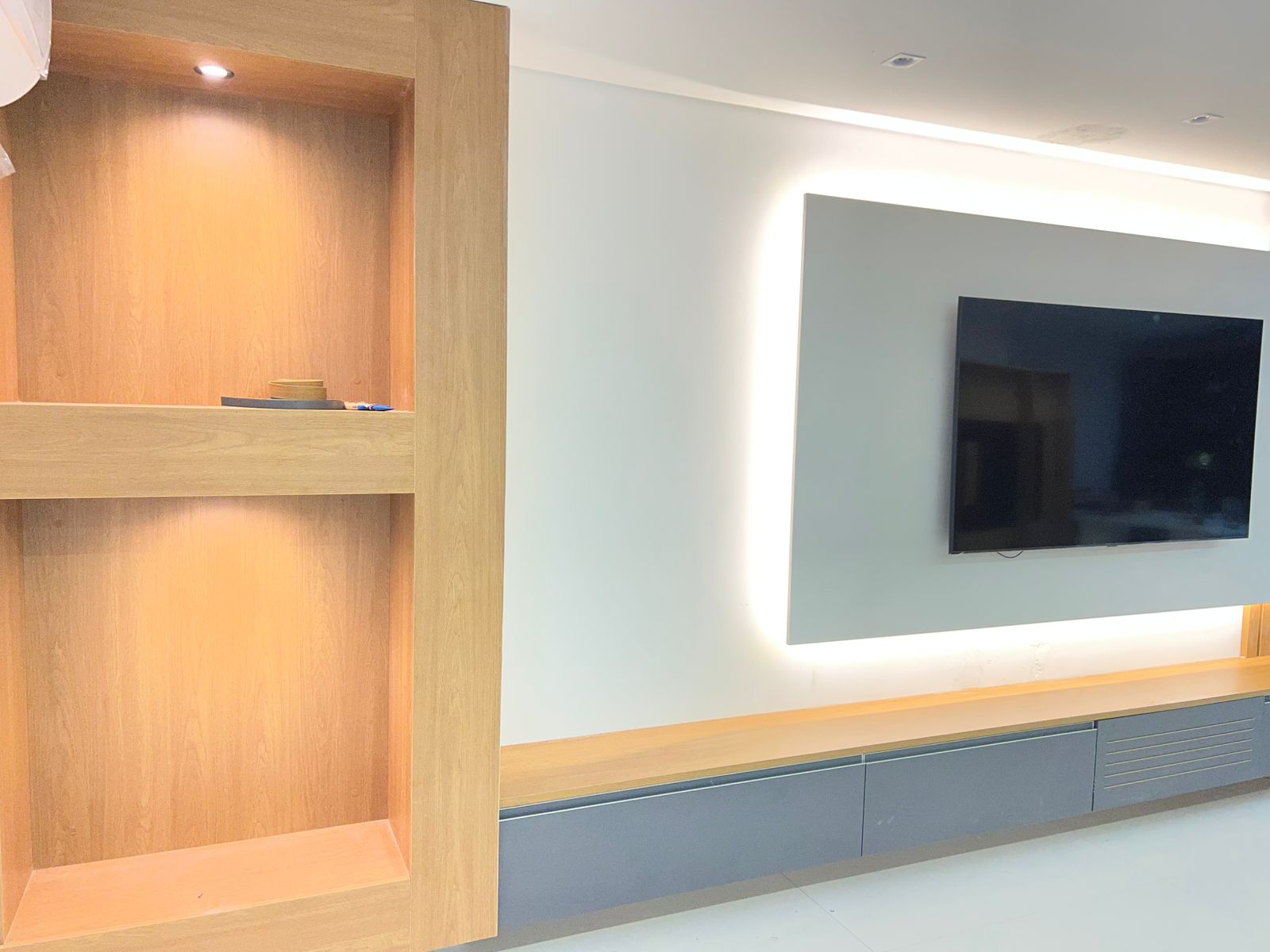 Painel para TV sob medida em tom verde suave (menta) com detalhe lateral decorativo em madeira ripada.