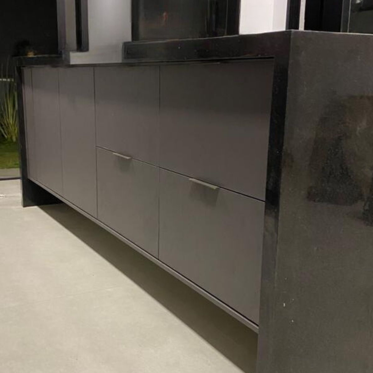 Balcão de cozinha ou área gourmet planejado em MDF cinza escuro moderno com puxadores discretos.