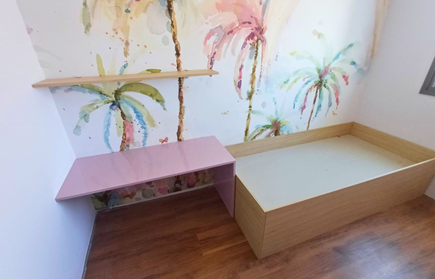 Quarto infantil planejado com cama box de madeira e bancada de estudos rosa, otimizando o espaço para crianças.