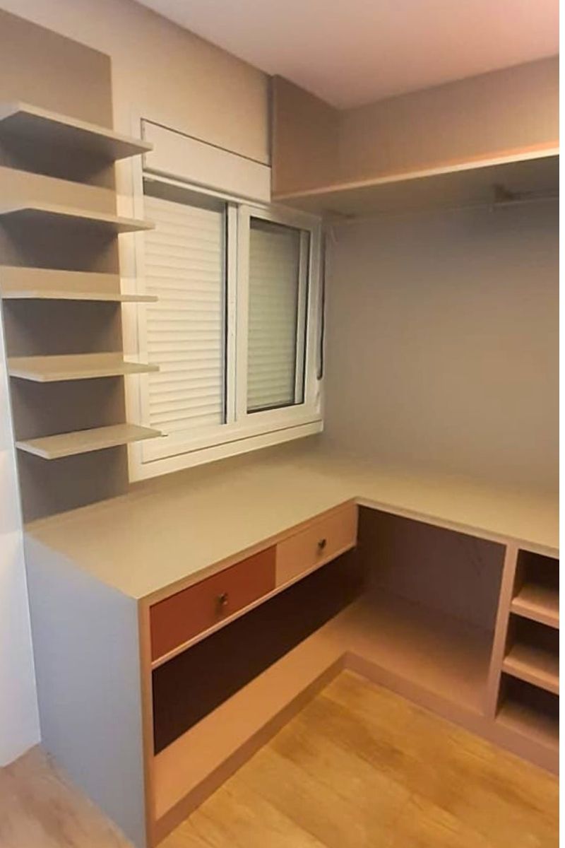 Home office planejado em canto (formato em L) com mesa de madeira e prateleiras brancas suspensas.