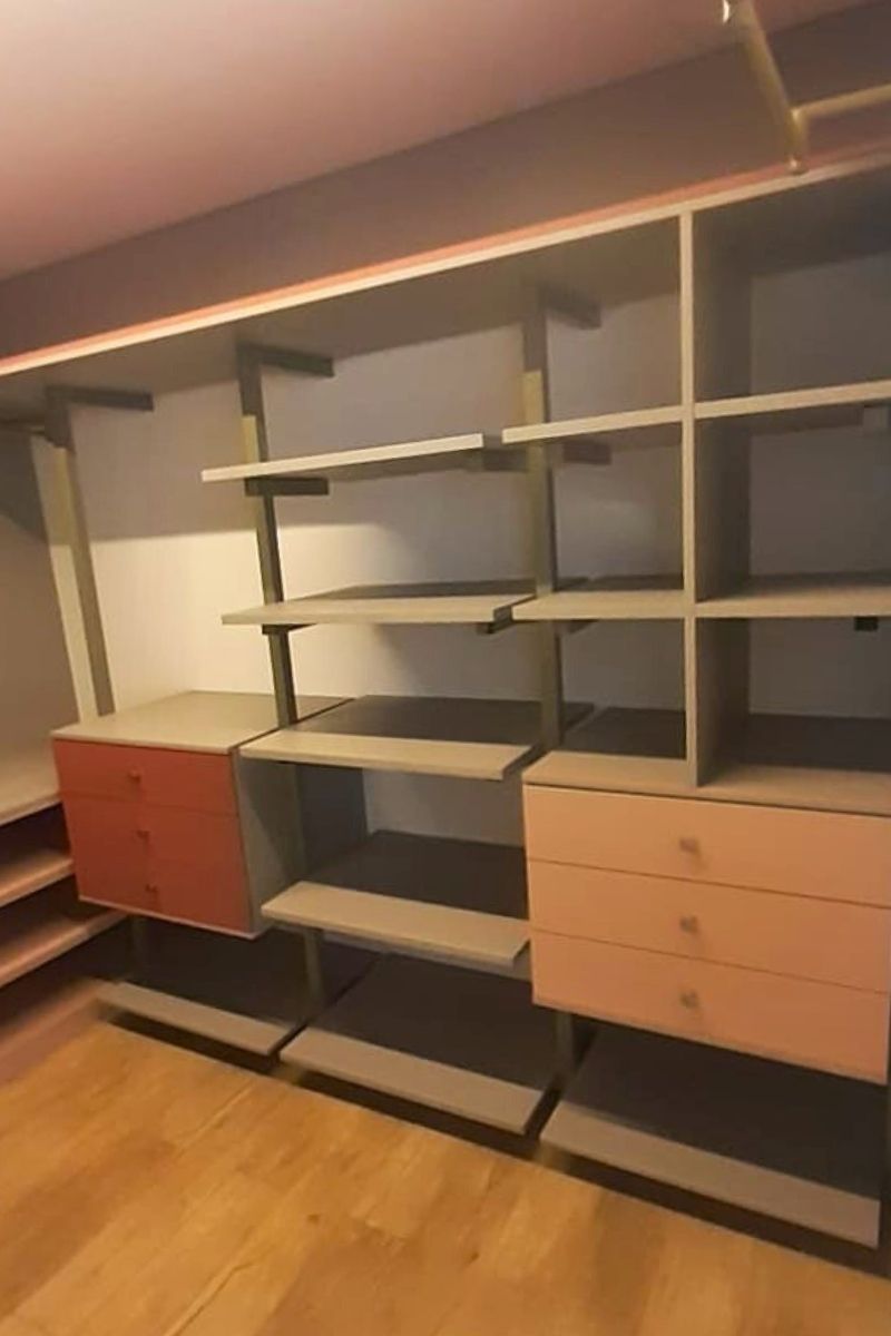 Estrutura de closet ou estante planejada com nichos abertos e gavetas em combinação de cinza e madeira.