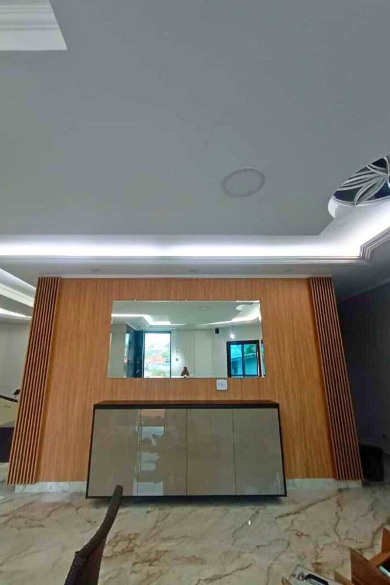 Sala de estar moderna com painel ripado de madeira (TV), espelho central decorativo e sanca de gesso iluminada.