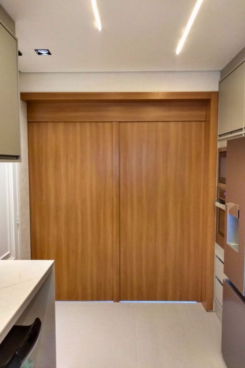 Guarda-roupa planejado com grandes portas de correr em madeira, otimizando o espaço do quarto.