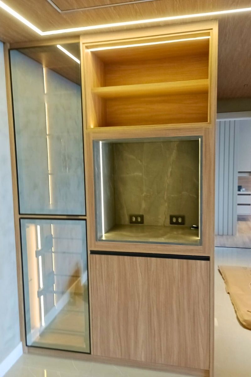 Nicho decorativo iluminado com LED e fundo marmorizado, parte de estante planejada para sala.