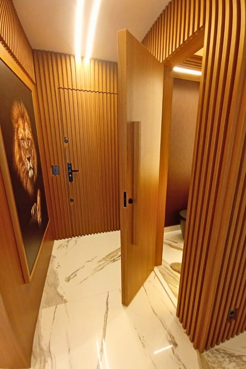 Hall de entrada luxuoso com revestimento de parede em madeira ripada e iluminação cênica.