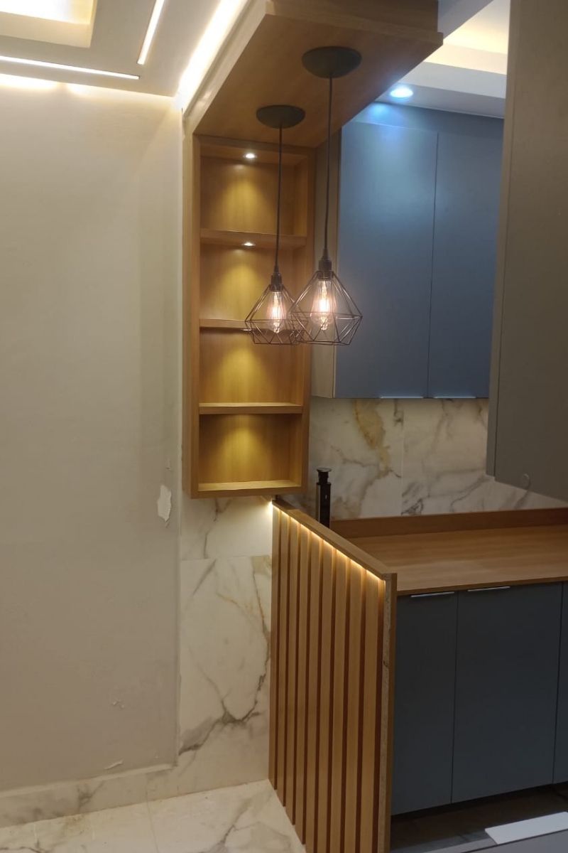 Projeto de marcenaria com prateleiras de madeira iluminadas e armários superiores na cor azul.