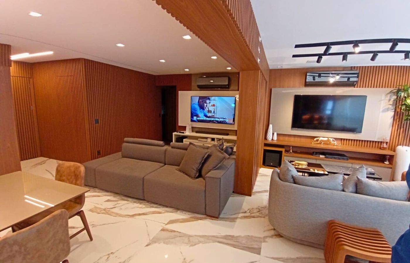 Sala de estar ampla com projeto de marcenaria sofisticado, apresentando paredes e teto revestidos com painéis de madeira ripada.